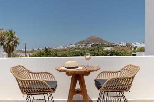 a table with a hat and a glass of wine on a balcony at Perla Hotel in Agios Prokopios