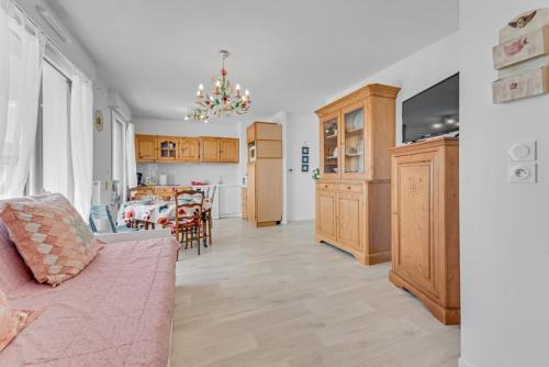 un salon avec un canapé rose et une cuisine dans l'établissement Retraite Paisible à Dives sur Mer pour 4 pers, à Dives-sur-Mer