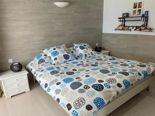 a bed with a blue and white comforter and pillows at La Casita in Pau