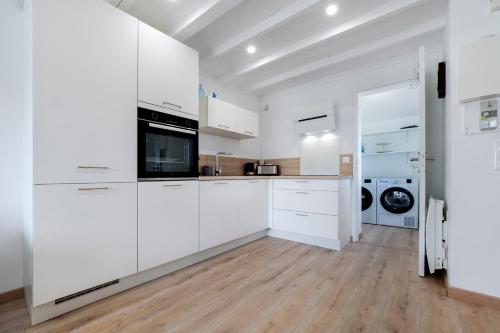 une cuisine avec des armoires blanches et une laveuse et une sécheuse dans l'établissement Evasion Bord de Mer Criques & Côte sauvage, au Pouliguen