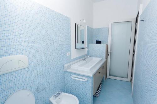 a blue tiled bathroom with a sink and a toilet at Villa Degli Angeli in Nardò