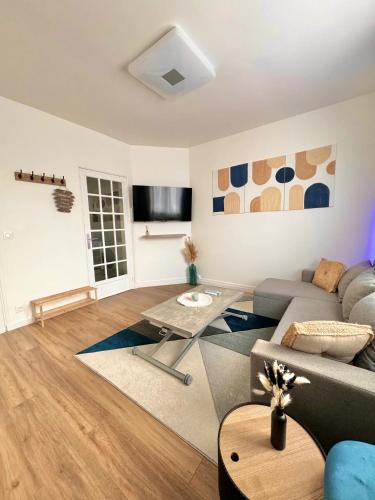 un salon avec un canapé et une table dans l'établissement Appartement Cosy près de CDG, Astérix,JO, Paris, à Puiseux-en-France