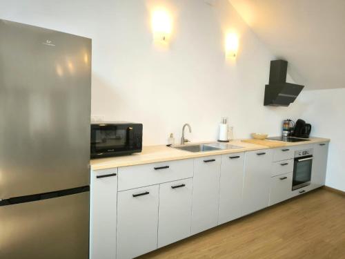 a white kitchen with a sink and a microwave at Les Tilleuls - cnpe bugey - bases de loisirs - pérouges in Chazey-sur-Ain