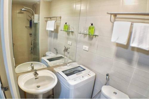 a bathroom with a sink and a washing machine in it at HOMEY MAKATI CONDO UNIT with NETFLIX in Manila