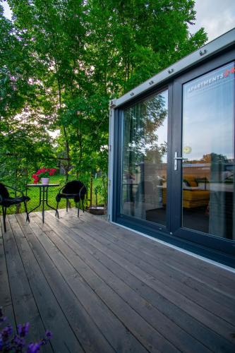 a deck with two chairs and a table and windows at Apartments24 CITYBOX in Rakvere