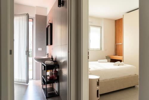 a room with a bed and a bathroom with a refrigerator at San Siro Fiera - Youhosty in Milan