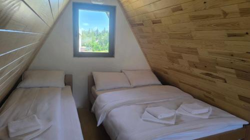 deux lits dans une petite pièce avec une fenêtre dans l'établissement Apartmani Stara kuca, à Žabljak