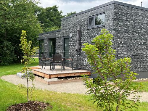 a black stone cottage with a table and chairs on a patio at Tiny Haus Park Fritzlar in Fritzlar