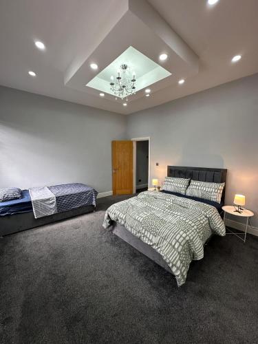 a bedroom with two beds and a ceiling with a chandelier at Room in Stockport Road in Manchester