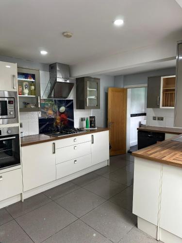 a large kitchen with white cabinets and appliances at Room in Stockport Road in Manchester