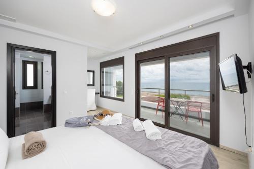 a bedroom with a bed with a television and a balcony at Villa Tsampikos in Lachania
