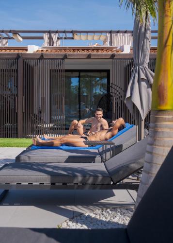two men laying on beds in a swimming pool at Fahana - Gay Men Only in Playa del Ingles
