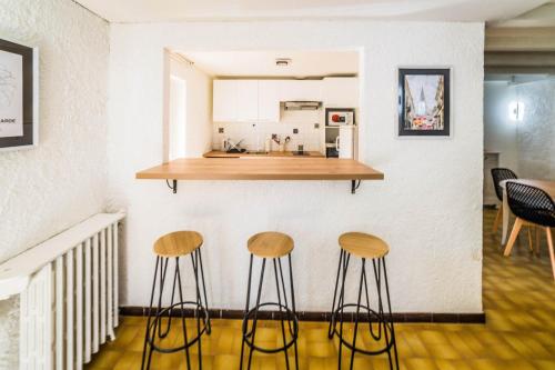 ブリーヴ・ラ・ガイヤルドにあるLa Pause des 6 - Maison Paisibleの壁際に3脚のスツールが置かれたキッチン