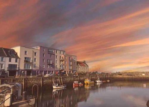 a painting of a harbor with boats in the water at Beach Front Apt 2 Bedrooms 2 Bathrooms St Andrews in Fife