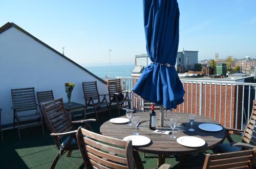 a wooden table with a blue umbrella on a balcony at Heart of Old Portsmouth in Portsmouth