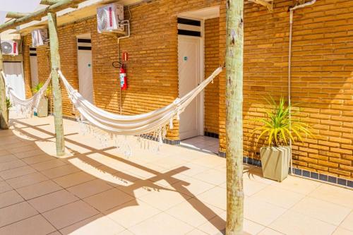 a hammock in front of a brick building at Pousada Corais Barra in Barra de São Miguel