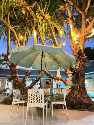 a table and chairs with an umbrella on a patio at Pousada Corais Barra in Barra de São Miguel