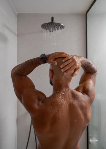 a man taking a shower in a bathroom with water on his head at Fahana - Gay Men Only in Playa del Ingles