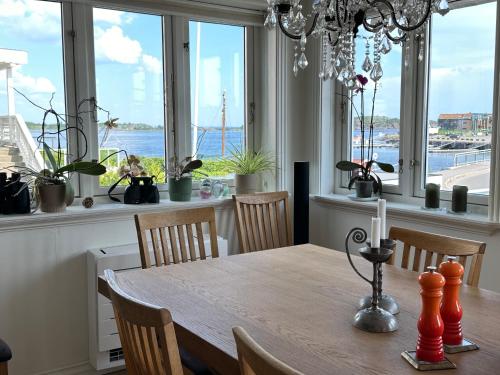 a dining room with a table and some windows at Ved sjøen, Husvik- Tønsberg, 2 hus! in Tønsberg