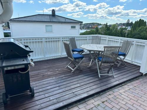 a deck with a table and chairs and a grill at Ved sjøen, Husvik- Tønsberg, 2 hus! in Tønsberg