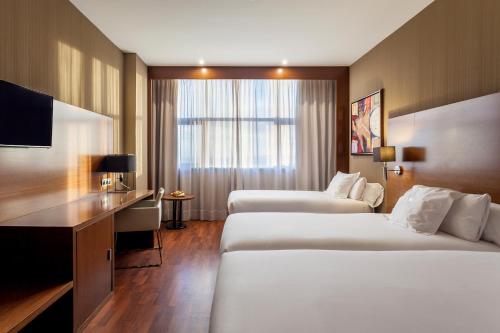 a hotel room with two beds and a desk at AZZ Valencia Congress Hotel & Spa in Paterna