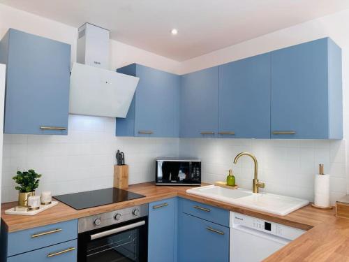une cuisine avec des armoires bleues et un évier dans l'établissement Appartement Au Cœur de Granville, à Granville