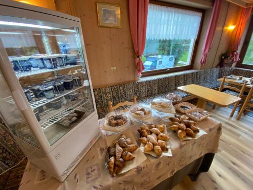 a bakery with a counter with pastries and a refrigerator at Hotel B&B Lorenzini Ski in Selva di Cadore