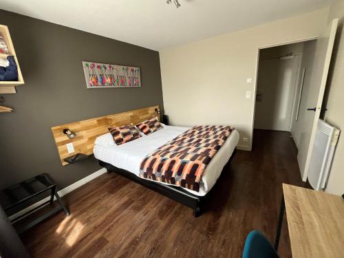 a bedroom with a bed with a wooden headboard at Brit Hotel Quimper Nord in Ergué-Gabéric