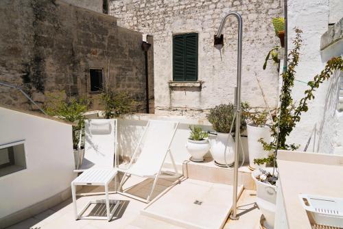 a patio with white chairs and potted plants at Casetta Bouganville - con TERRAZZA PANORAMICA in Ostuni