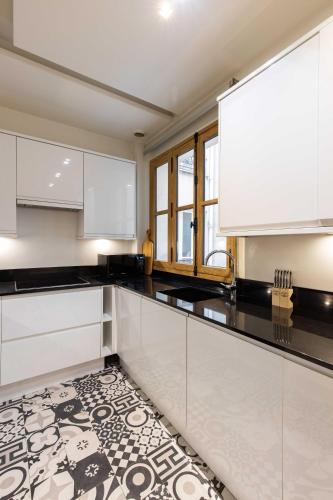 une cuisine avec des armoires blanches et un sol carrelé dans l'établissement Sublime Apt - 3BD-6P - Arc De Triomphe, à Paris