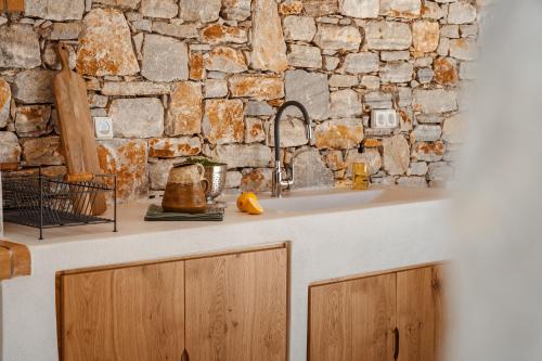 Una cocina con fregadero y una pared de piedra. en SIMIU Villa with Private Swimming Pool, en Agia Anna de Naxos