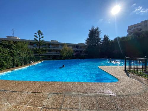une grande piscine avec une personne dans l'eau dans l'établissement Superbe appartement de 3p pieces dans residence avec piscine et climatisation, à Nice