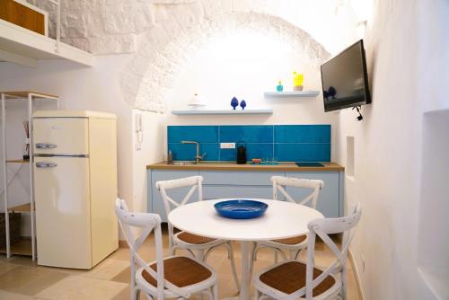a kitchen with a white table and chairs and a refrigerator at Casetta Bouganville - con TERRAZZA PANORAMICA in Ostuni