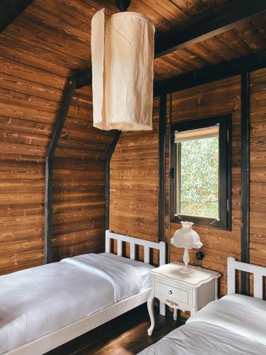 two beds in a room with wooden walls at Mora Farmhouse in Ardeşen