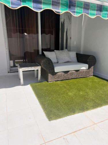 a couch on a patio with a green rug and a table at Puerto Banus Jacuzzi close to Breath and Marbella Arena in Marbella