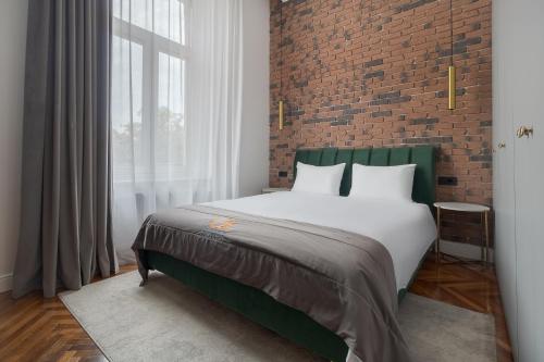 a bedroom with a large bed and a brick wall at Olimpia Residence in Oradea