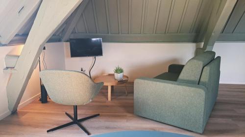 a living room with two chairs and a tv at Stadsklooster Dordt Hotel&Hostel in Dordrecht