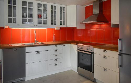a kitchen with red walls and white cabinets at Amazing Home In Tomelilla With Wifi in Tomelilla