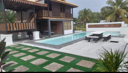 a villa with a swimming pool and a house at Tein room in Rengit