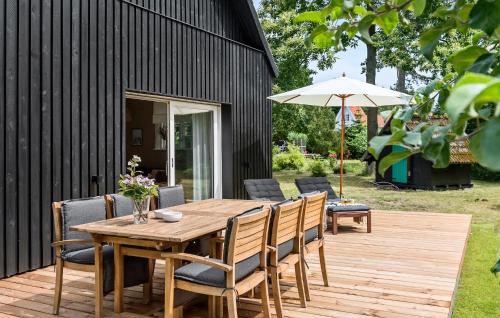 a wooden table with chairs and an umbrella on a deck at 5 Bedroom Nice Home In Væggerløse in Marielyst