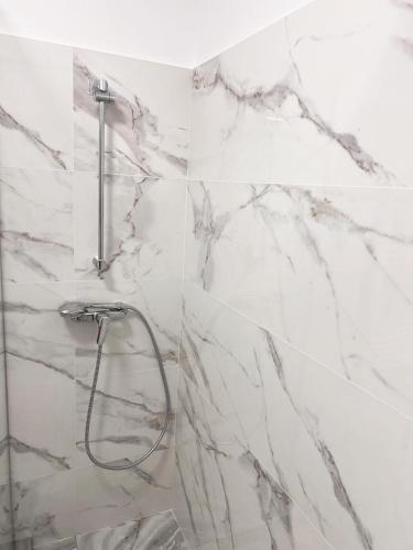 a bathroom with a shower with white marble walls at Rion Apartment in Saturn