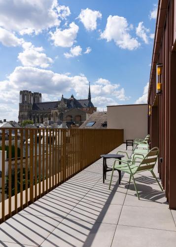 a balcony with two tables and chairs on a building at Les Suites 7 Anges - Parking, Vue Cathédrale & Centre Historique Reims in Reims
