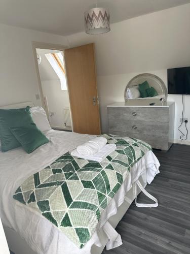 ein Schlafzimmer mit einem Bett mit einer grünen und weißen Decke in der Unterkunft Lavish 3 story house with full of comfort in Dagenham