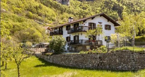 Casa blanca con una pared de piedra y árboles en B&B Haus Senter, en Trambileno