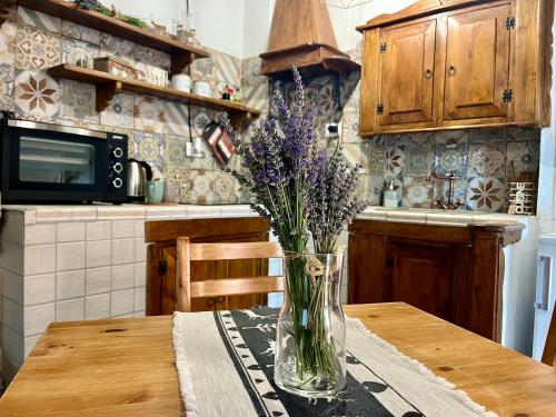 un vaso con fiori viola seduto su un tavolo in cucina di Baita delle Rocche a Rocca di Mezzo