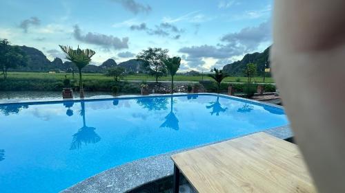 a large swimming pool with blue water and mountains in the background at Tam Coc Moutainside Homestay in Ninh Binh