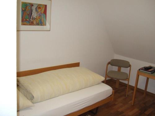 a small bedroom with a bed and a chair at Gasthaus zur Sonne in Aesch