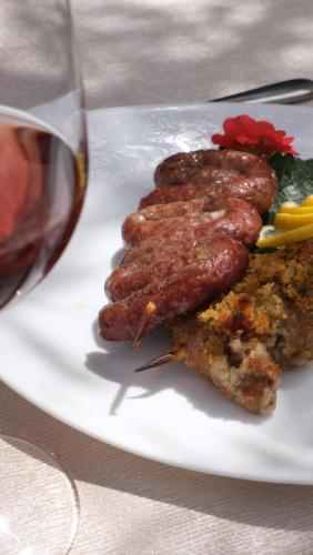 three sausages on a plate next to a glass of wine at Agriturismo il Vignaletto in Martina Franca