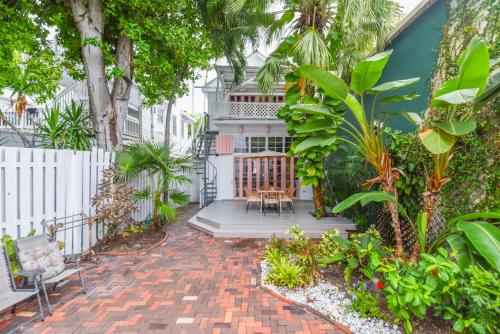 a brick patio with chairs and plants in front of a house at New Rose Retreat - Pool & Parking in Key West