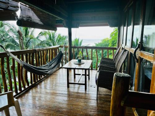 a porch with a hammock and a table and chairs at White Beach Front and Cottages in Buruanga